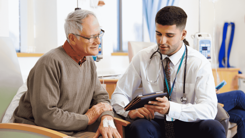 A man speaks with his doctor who holds his chart for them to look at.